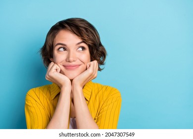 Photo of cheerful minded lady interested arms cheeks look empty space wear yellow shirt isolated blue color background - Shutterstock ID 2047307549