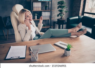 Photo Of Cheerful Nice Charming Positive Assistant Talking On Phone At The End Of Work Day Putting Her Eyewear Off With Legs On Table