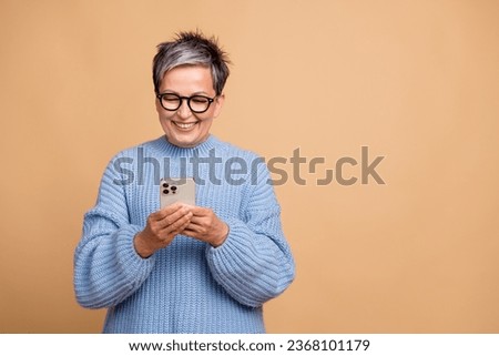 Photo of cheerful nice person toothy smile use smart phone empty space ad isolated on beige color background