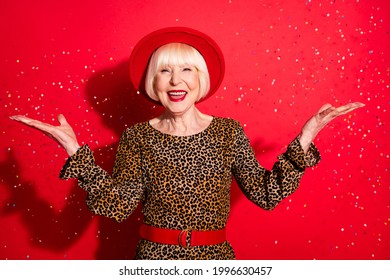 Photo Of Cheerful Nice Pretty Positive Old Woman Hold Hands Empty Space Fall Catch Confetti Isolated On Red Color Background