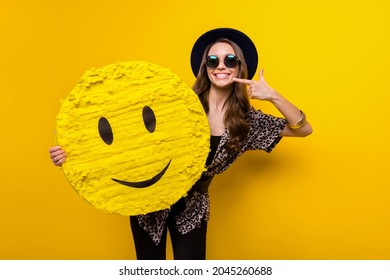 Photo of cheerful positive happy lady point finger smile hold hand emoji paper pinata isolated on yellow color background