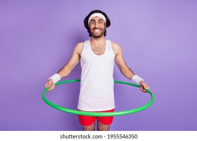 Photo of cheerful positive happy young man hold waist hula hoop smile aerobics isolated on purple color background