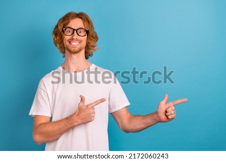 Photo of cheerful positive man direct fingers empty space proposition isolated on blue color background