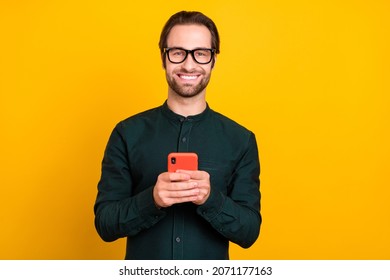 Photo of cheerful positive young guy dressed smart casual clothes spectacles communicating modern gadget isolated yellow color background