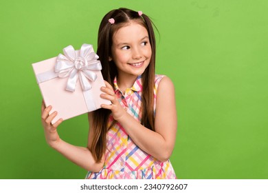 Photo of cheerful pretty girl wear stylish clothes arms hold nice gift package looking empty space isolated on green color background - Powered by Shutterstock