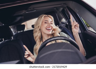 Photo Of Cheerful Pretty Lady Sitting Driver Seat Point Fingers Enjoy Listen Song Have Good Mood