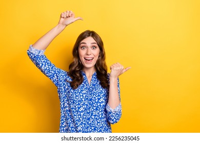 Photo of cheerful pretty lady wear stylish clothes arm above head demonstrate empty space nice choice isolated on yellow color background - Shutterstock ID 2256235045