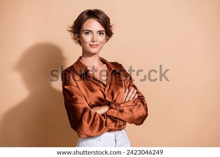 Photo of cheerful pretty woman wear silky blouse arms folded empty space isolated beige color background