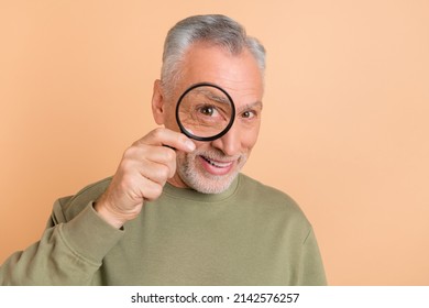 Photo Of Cheerful Senior Man Watching Through Loupe Ophthalmology Check Isolated Over Beige Color Background