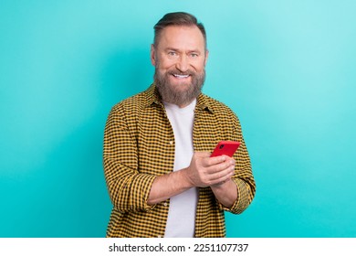 Photo of cheerful smiling satisfied man grey hairstyle nice beard wear yellow shirtsmart phone happy user isolated on aquamarine color background - Powered by Shutterstock