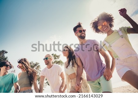 Photo of cheerful tourist people walk hold hands wear sunglass casual outfit nature summer seaside beach