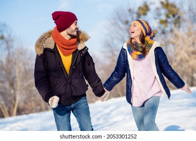 Photo of cheerful young couple happy positive smile walk outside hold hands together winter snow vacation laugh joke