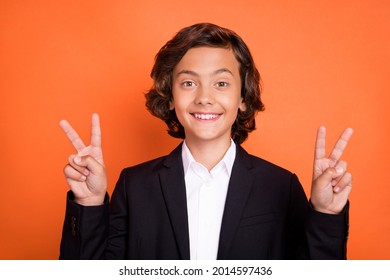 Photo of cheerful young happy positive small boy make fingers two v-signs isolated on orange color background