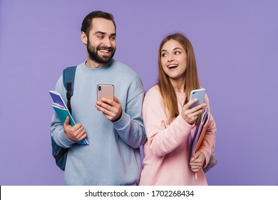 Photo of a cheery happy loving couple friends students isolated over purple wall background using mobile phones. - Shutterstock ID 1702268434