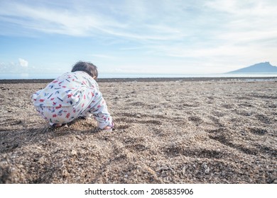 Photo Of Child Playing Sand On The Beach When Mooring Sun. The Photos Is Perfect For Poster, Pamphlet And Banner About Holiday On The Beach.