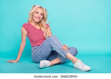 Photo of childish adorable young woman dressed red t-shirt smiling sitting floor isolated teal color background - Powered by Shutterstock