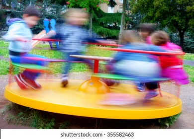 Photo of children having fun at colorful carousel spinning round fast