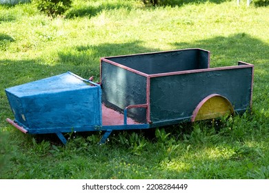 Photo Of A Children's Iron Car On A Background Of Green Grass. A Child Can Get Into The Car. Outdoor Entertainment For Children And Outdoor Games.