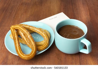 Photo Of Churros, Traditional Spanish, Especially Madrid, Dessert, In Particular For Sunday Breakfast. In Form Of Horseshoes, With Cup Of Hot Chocolate, On Wooden Texture With A Postcard