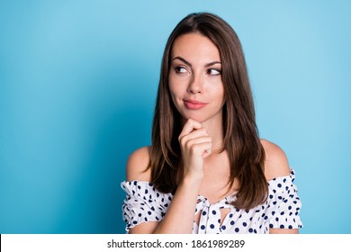 Photo of clever pretty girl finger chin look empty space think wear dotted blouse isolated blue color background - Shutterstock ID 1861989289