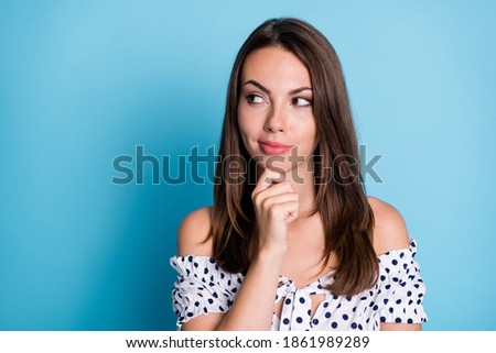 Photo of clever pretty girl finger chin look empty space think wear dotted blouse isolated blue color background