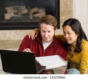 Photo Of Close Mature Couple Looking At Information On The Computer Screen Together With Fireplace In Background  