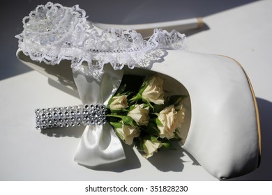 Photo Closeup Of Beautiful Wedding Buttonhole Bouquet Of Fresh Small Pastel Color Tea Roses Flowers Buds Green Leaves Decorated With Bow Crystals And Bride Shoe On White Background, Horizontal Picture
