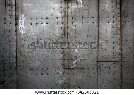 Photo closeup old rusty grunge steel aluminum fragment of protective structure made of metal plates sheets assembled with button head rivets on armor textured background, horizontal picture 