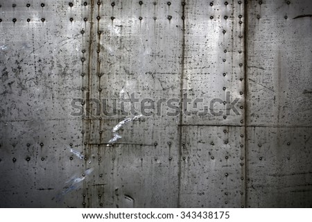 Photo closeup old rusty grunge steel aluminum fragment of protective structure made of metal plates sheets assembled with button head rivets on armor textured background, horizontal picture 