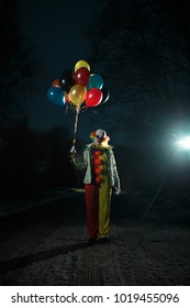 Photo of clown with balls in hands at night