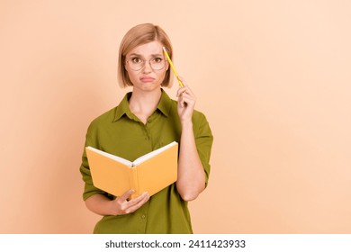 Photo of clueless puzzled woman dressed green shirt in glasses holding book pencil on forehead thinking isolated on beige color background - Powered by Shutterstock