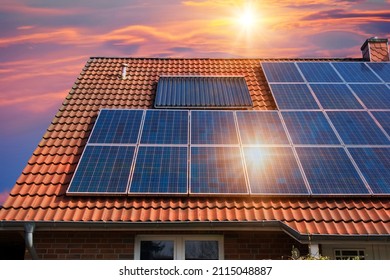 Fotocollage von Solarzellen, Fotovoltaik auf dem roten Dach eines Hauses und ein schöner Himmel mit der untergehenden Sonne. Alternative Stromquelle. Konzept der nachhaltigen Ressourcen