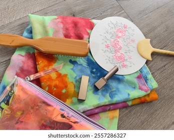 Photo of colorful floral scarf, fan with pink floral embroidery, lipstick, wooden comb and pink purse women's fashion accessories on wooden floor - Powered by Shutterstock