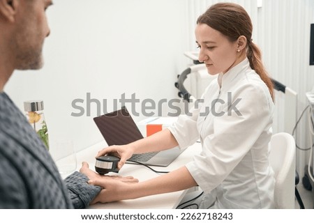 Photo of concentrated female doctor is doing spectral analysis in health center