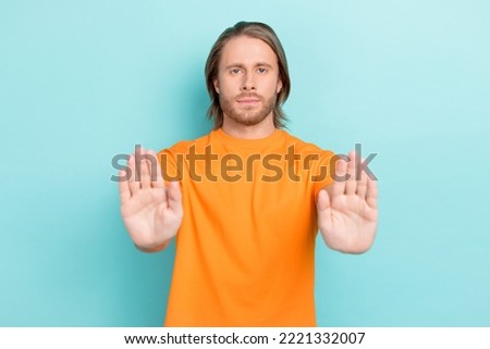 Photo of confident charming guy wear orange t-shirt rising palms showing no isolated teal color background