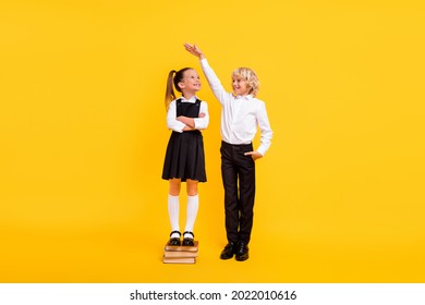 Photo Of Confident Kids Girl Stay Pile Book Boy Measure Height Wear School Uniform Isolated Yellow Color Background