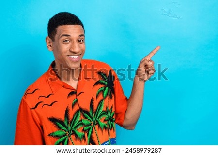 Photo of confident positive guy dressed print shirt showing finger empty space solated blue color background