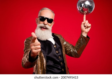 Photo Of Cool Beard Old Man Point You Hold Disco Ball Wear Gold Jacket Eyewear Isolated On Red Color Background