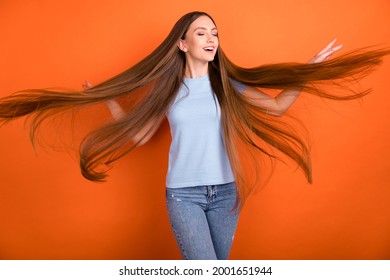Photo of cool millennial long hairdo lady touch hair wear blue t-shirt jeans isolated on orange color background