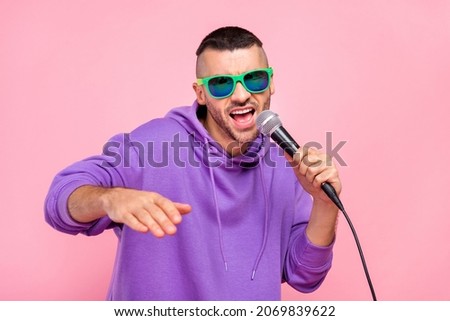 Photo of cool young brunet guy sing in mic wear eyewear hoodie isolated on pink background