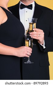 Photo of a couple in black tie evening dress holding a glass of champagne.