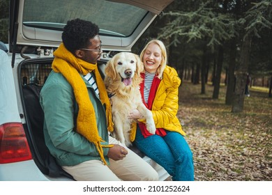 Photo Of A Couple On A Road Trip With Their Dog. Photo Of A Young Couple In Love And Their Dog Sitting The Trunk Of A Car On A Beautiful Autumn Day; Taking A Short Break During Their Road Trip.