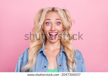 Photo of crazy blond young lady rongue out wear jeans shirt isolated on pink color background