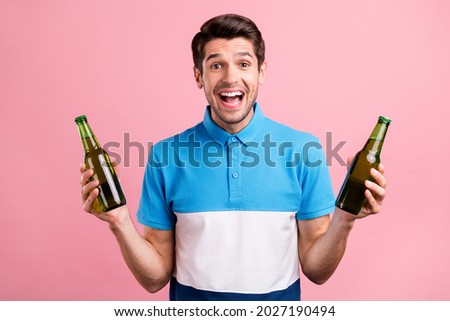 Photo of crazy brunet millennial guy hold bottles wear striped polo isolated on pink color background