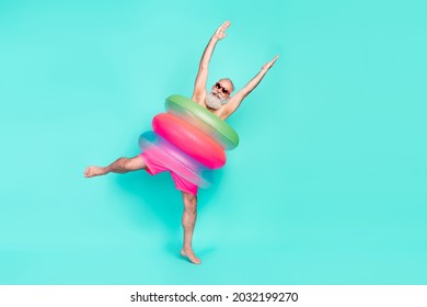 Photo of crazy clubber old man dance raise hands wear pile lifebuoy sunglass shorts isolated teal color background