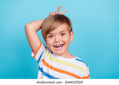 Photo of crazy excited little schoolboy make v-sign do bunny ears wear striped t-shirt isolated blue color background