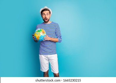 Photo of crazy funky guy open mouth hold big world globe map traveler see cheap tours abroad wear striped sailor shirt shorts panama isolated blue color background