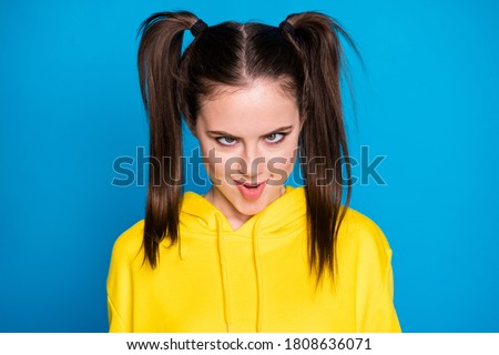 Photo of crazy funny carefree lady two tails making foolish faces eyes watch different ways childish person wear casual yellow hoodie pullover isolated bright blue color background