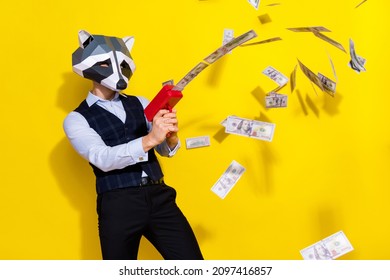 Photo of crazy guy racoon mask celebration halloween shoot pistol profit money isolated over yellow bright color background