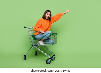 Photo Of Crazy Lady Pushcart Rider Put Hand Up Superhero Fly Shopping Center Sales Wear Jumper Isolated Over Green Color Background